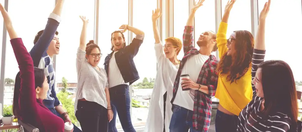 Succès d'équipe en entreprise : célébration au bureau Équipe diversifiée célébrant joyeusement un succès en bureau, bras levés et sourires radieux.