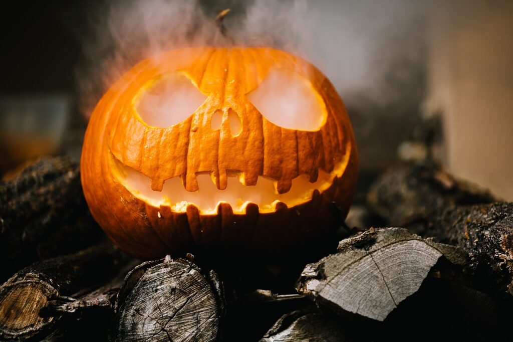 Citrouille d'Halloween sculptée fumante posée sur des bûches de bois.